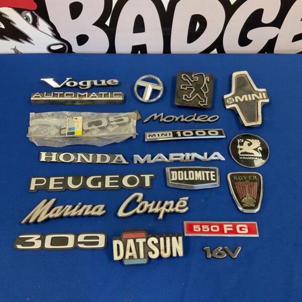 Vintage car badges collection including Mini, Rover and Vauxhall emblems.