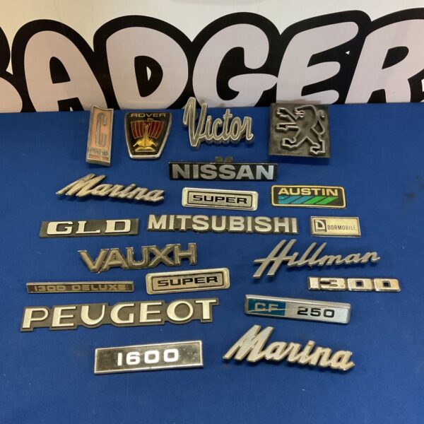 Vintage car badges including Nissan and Mitsubishi emblems for collectors.