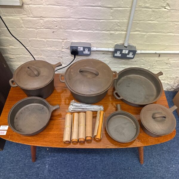 Selection of cast iron pans, skillets and lidded pots on a wooden table