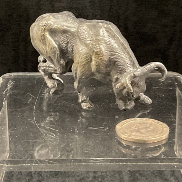 Close-up of cast metal bull figurine with a coin for scale.
