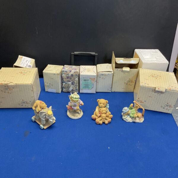 Cherished Teddies figurines displayed with original boxes on a blue surface