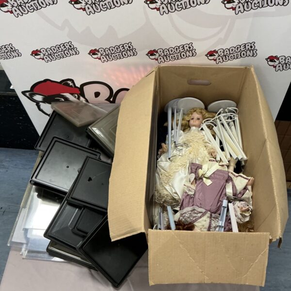 Antique china head dolls and display cases in a cardboard box.