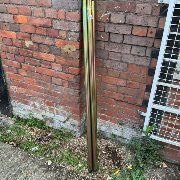 Four iridescent chrome poles leaning against a brick wall.