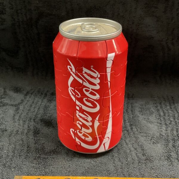 Red Coca-Cola can shaped 3-D jigsaw puzzle beside a wooden ruler