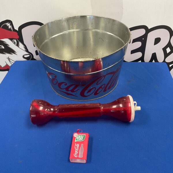 Coca-Cola ice bucket with red bottle and Tic Tac tin on blue surface