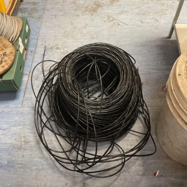 Large black coiled wire bundle with loose lengths on a workshop floor