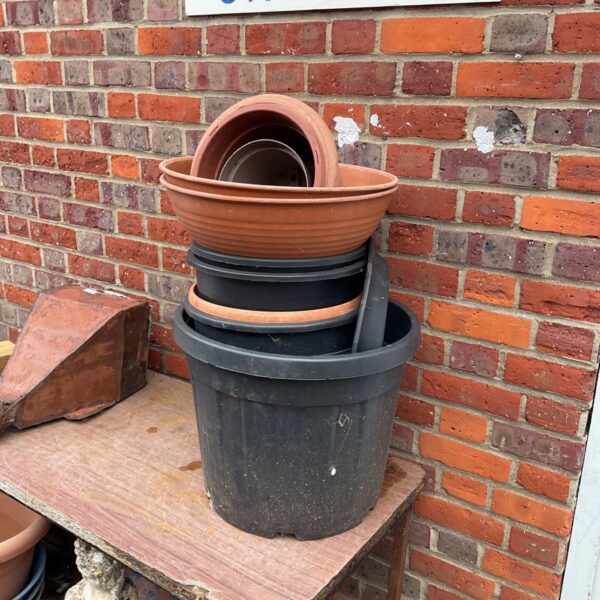 Stack of black and terracotta-effect plastic garden tubs in varying sizes