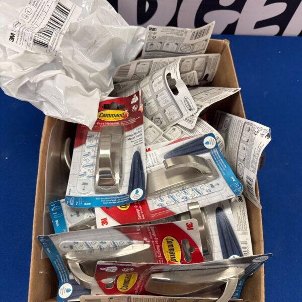 Box of new Command brushed nickel coat hooks for damage-free wall mounting.