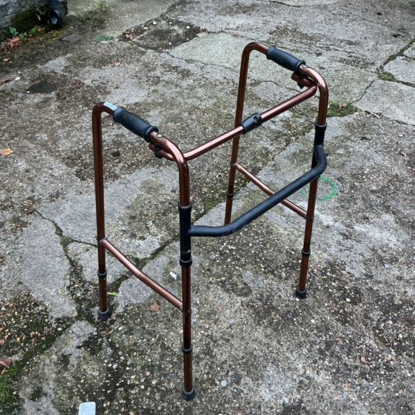 Copper-finish Zimmer frame walker with black hand grips and rubber feet
