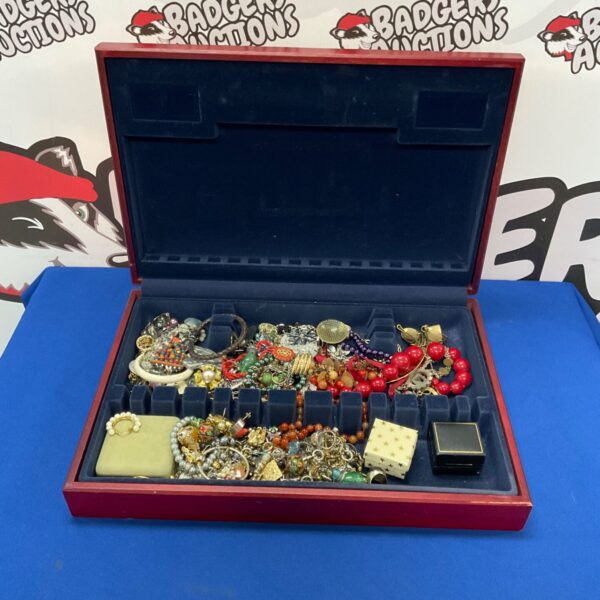 Open burgundy jewellery box filled with costume jewellery and trinkets.