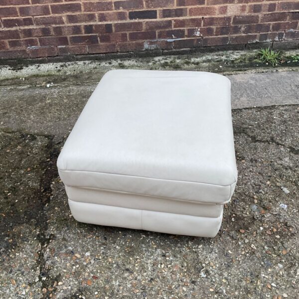 Square cream upholstered footrest with padded top and tiered base
