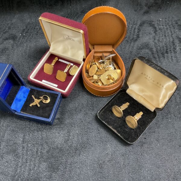 Vintage cufflinks and tie pins in a display tub, collectible men's accessories.