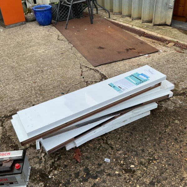 Stack of white gloss Cusko floating shelves of varying lengths on paving