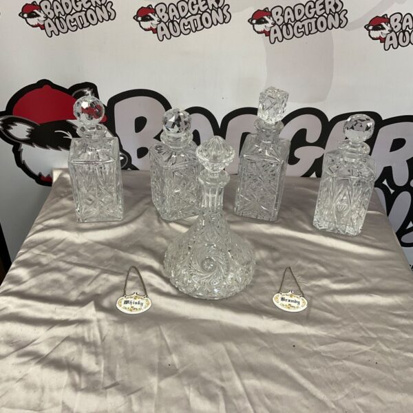 Five cut crystal decanters with whisky and brandy collar labels on a table
