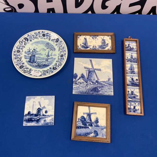 Collection of blue and white Delft pottery plate and windmill wall tiles displayed on blue background