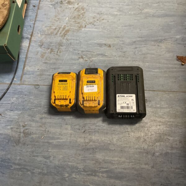 Two yellow DeWalt power tool batteries beside a black Stihl AP300 battery