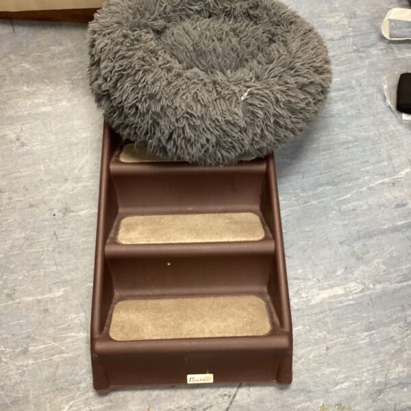 Brown dog steps with carpeted treads and grey faux fur bed on top