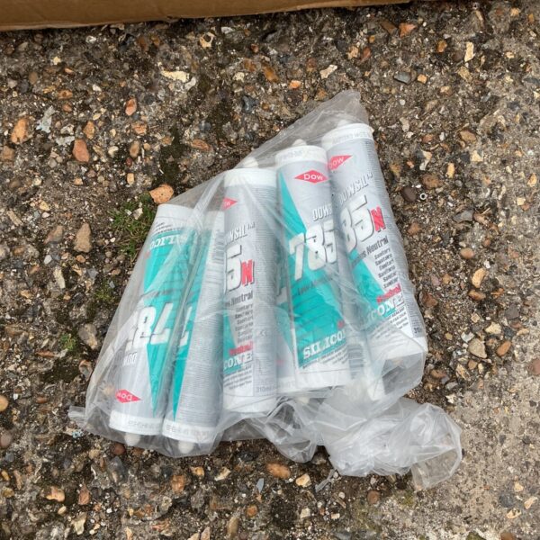Quantity of expired Dowsil silicone sealant tubes in a plastic bag.