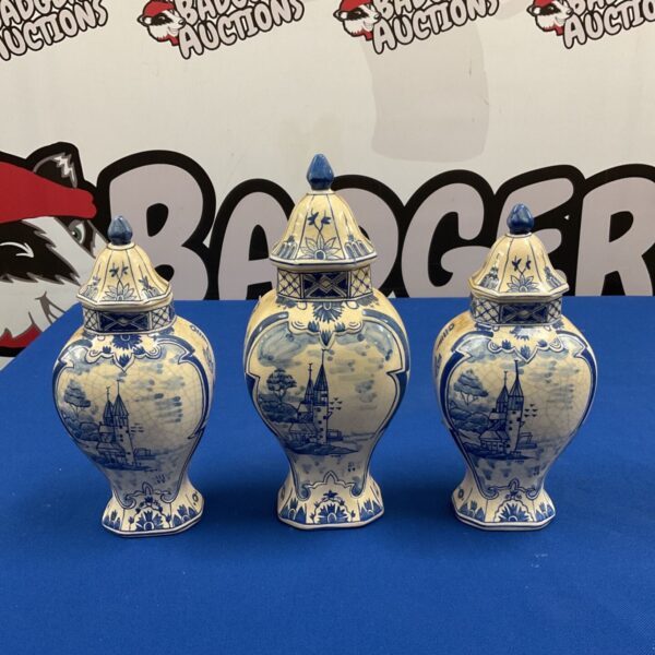 Set of three Dutch Delft blue and white lidded urns on blue cloth