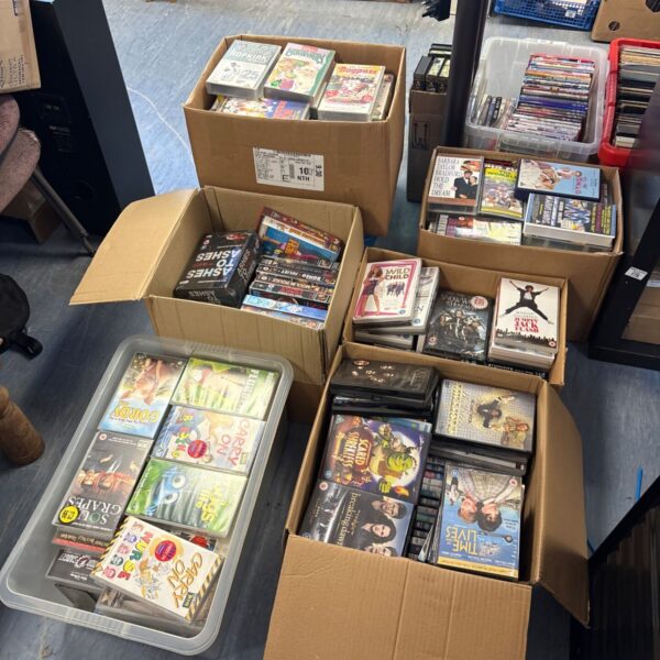 Mixed lot of DVDs and VHS tapes in cardboard boxes.