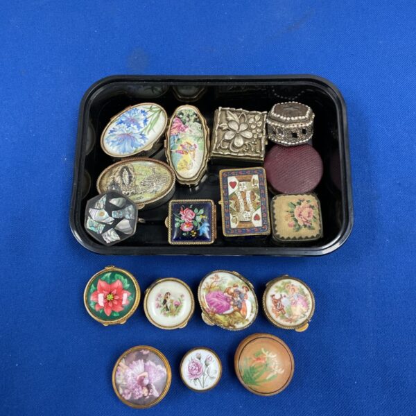 Collection of vintage enamel and decorative trinket pots on tray and blue background