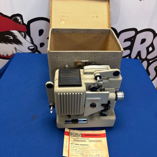 Vintage Eumig P8 8mm film projector beside open cream carrying case