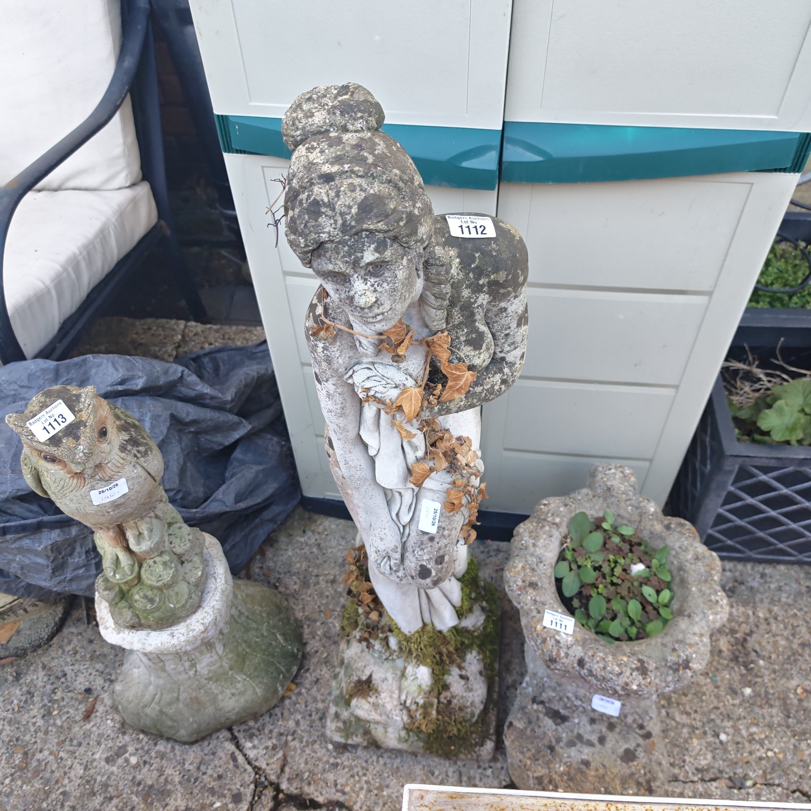 Weathered female stone garden statue with hair in a top bun on plinth