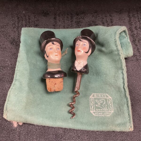 Figural ceramic top hat bottle stopper and corkscrew beside green Birks pouch