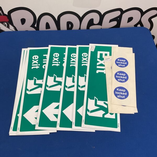 Green fire exit signs and blue keep locked shut stickers on a blue table