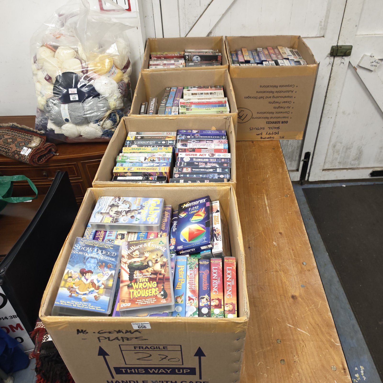 Five cardboard boxes of vintage VHS tapes arranged on a wooden surface