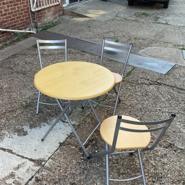 Foldable dining set with wooden table and three chairs in a garden setting.