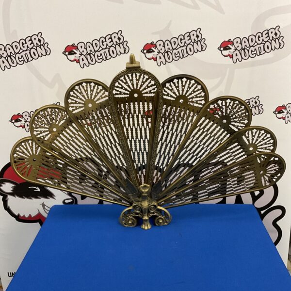 Folding brass peacock firescreen with pierced sunburst panels fanned out on blue plinth