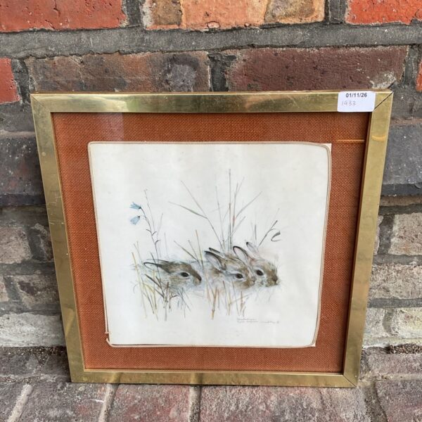 Framed print of three rabbits among grasses and blue bellflowers in brass frame