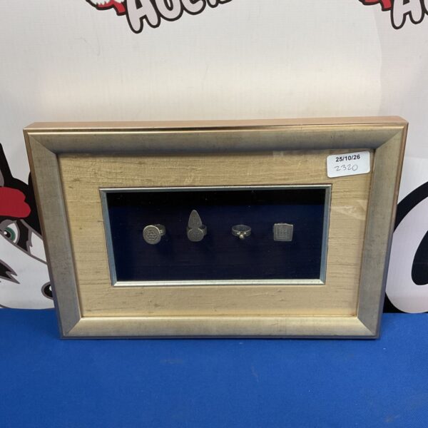 Four silver rings displayed in a gilt frame on dark blue backing