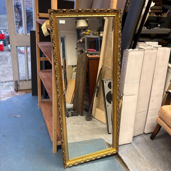 Full-length gilt wall mirror with ornate gold frame and bevelled glass
