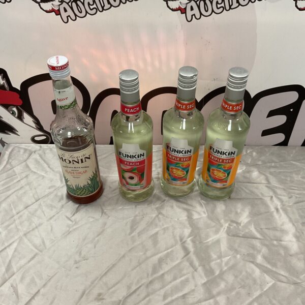 Four bottles of Funkin cocktail liqueur and Monin agave syrup on a white cloth