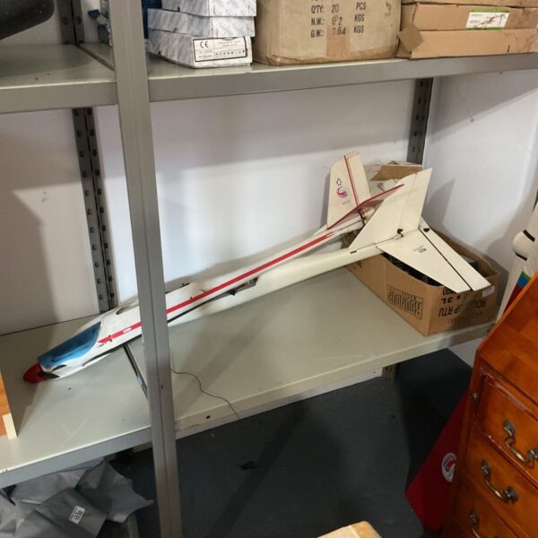 White and red model plane with blue nose beside Futaba Skysport 6A lot