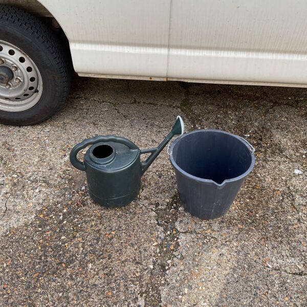 Vintage metal watering can and plastic bucket for garden use.