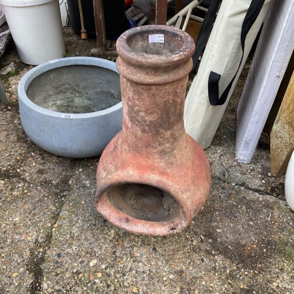 Weathered terracotta garden chimaera sculpture in an outdoor setting.