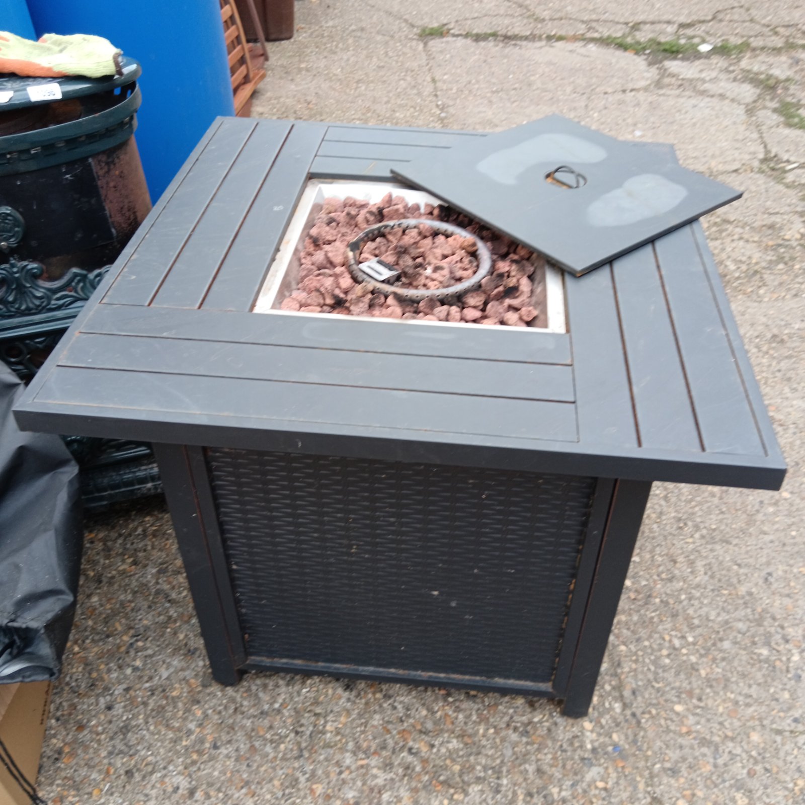 Dark steel garden fire pit table with visible fire bowl.