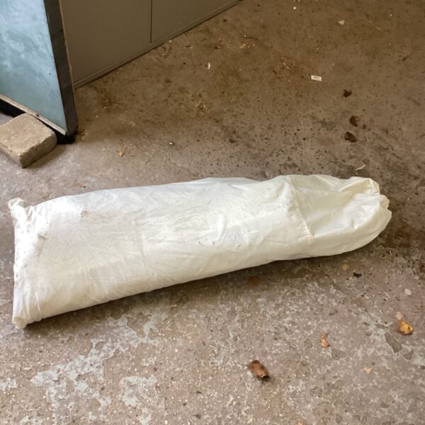 White bag containing a garden gazebo lying on a concrete floor