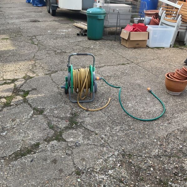 Used garden hose reel with green hose in an outdoor setting.