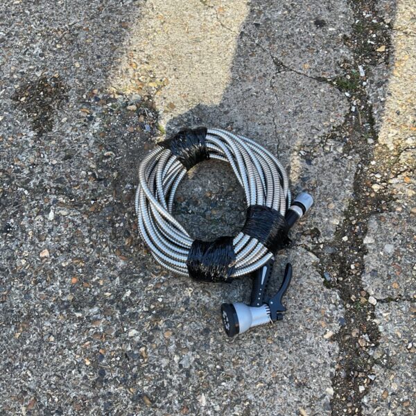 Coiled garden hose with black sprinkler head for lawn watering.