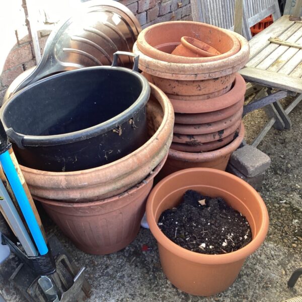 Mixed lot of terracotta and plastic garden planters for outdoor use.