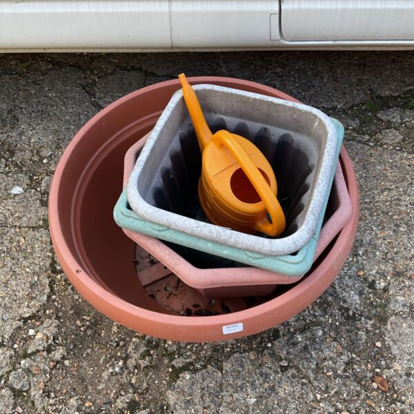 Stack of colourful plastic garden pots and a small orange watering can.