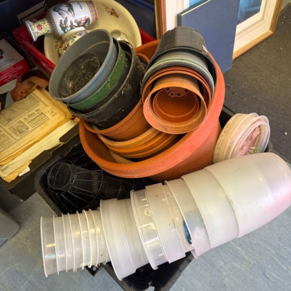 Stack of colourful plastic plant pots and garden accessories.