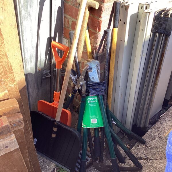 A set of used garden tools including shovels and shears.