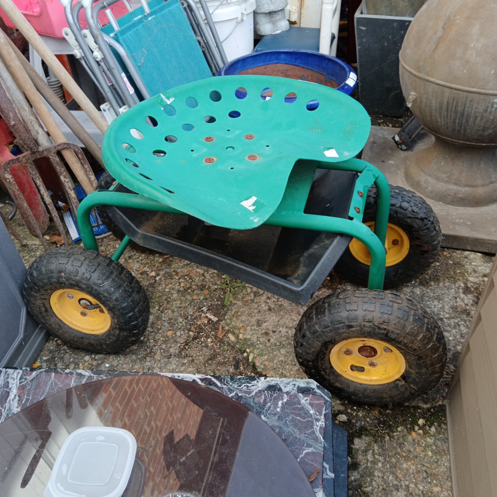 Green metal garden trolley seat with wheels for easy gardening.