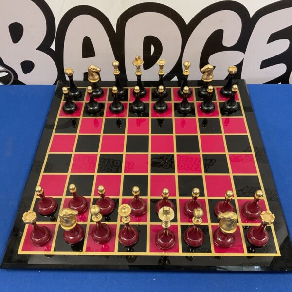 Glass chessboard with black and red squares and gold-tone metal chess pieces