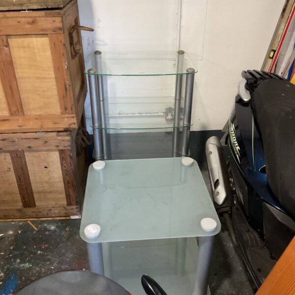 Square frosted glass side table with chrome legs beside multi-tier glass TV stand